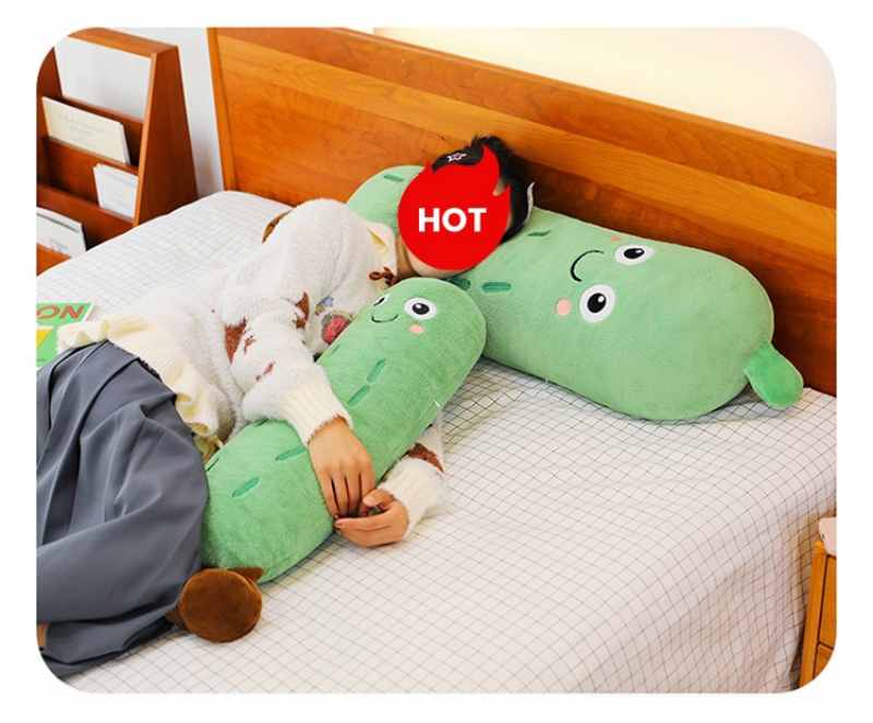 Girl sleeping while hugging a large, soft cucumber plush body pillow on a bed, popular emotional comfort stuffed animal and cute gift idea.