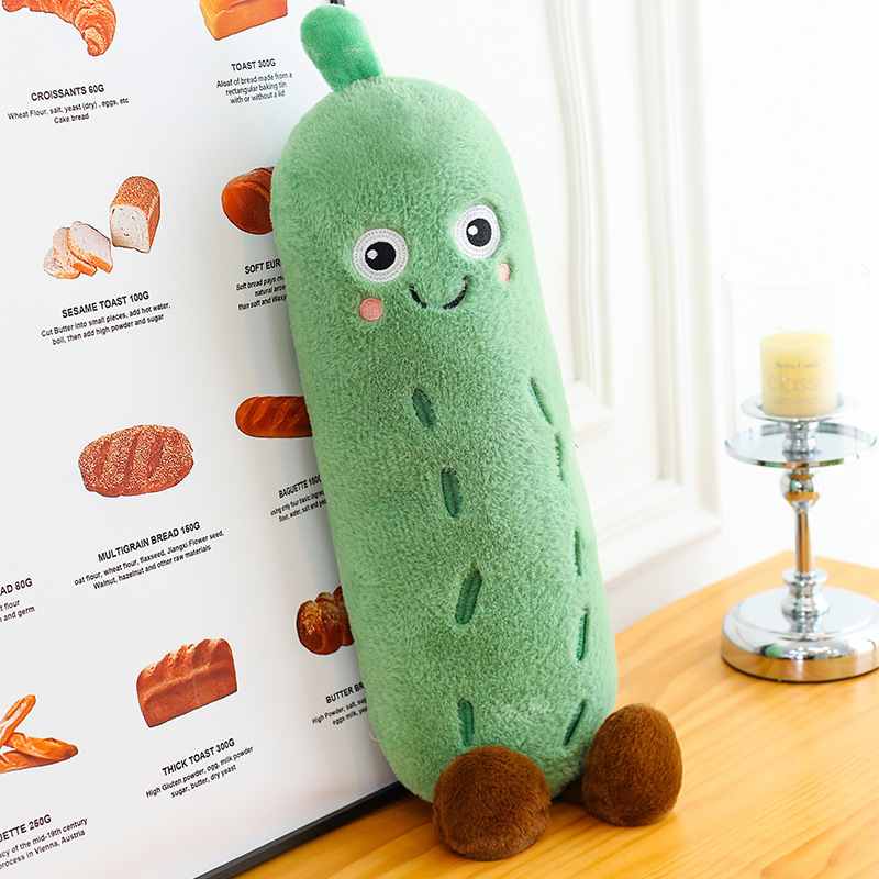 Cute cucumber plush toy leaning next to a bakery poster, kawaii aesthetic room decor and novelty gift idea for friends.