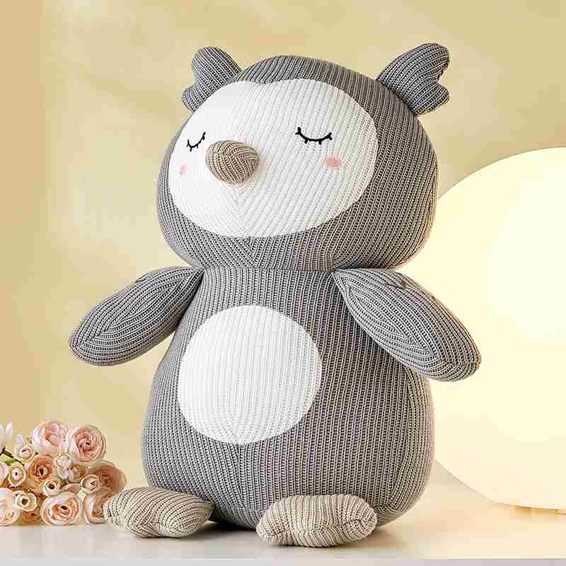 B2B custom grey ribbed plush owl toy sitting next to flowers, optimized for global retail distributors.
