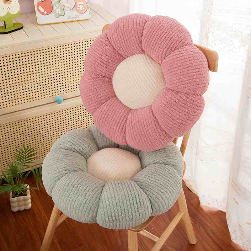 Bulk custom daisy flower seating pillows stacked on a wooden chair for boutique vendors.