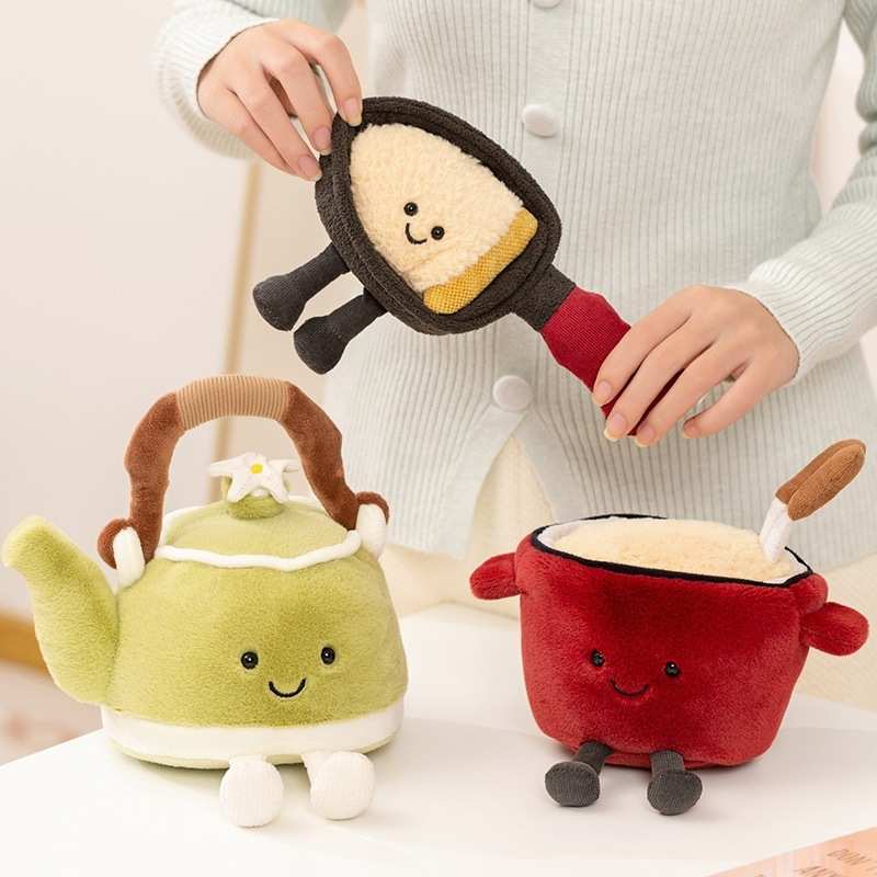 Person holding a plush frying pan toy alongside a plush teapot and noodle pot for bulk custom vendor orders.