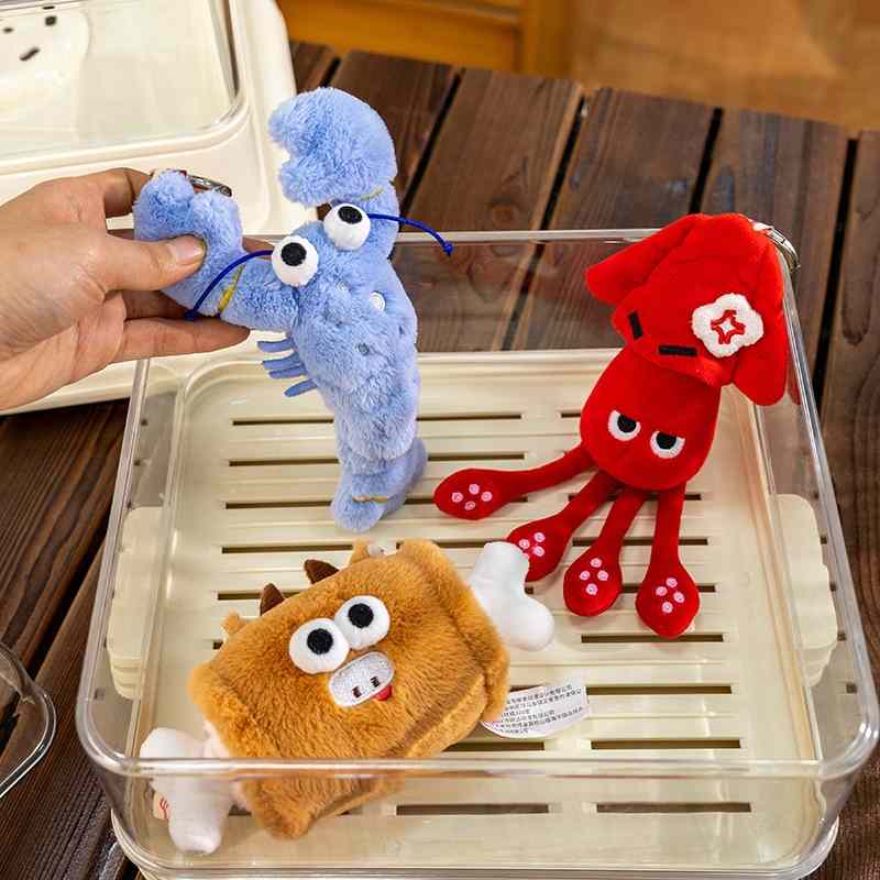 Wholesale quirky seafood and food plush keychains including crab, lobster, and meat bone in a clear box for B2B.
