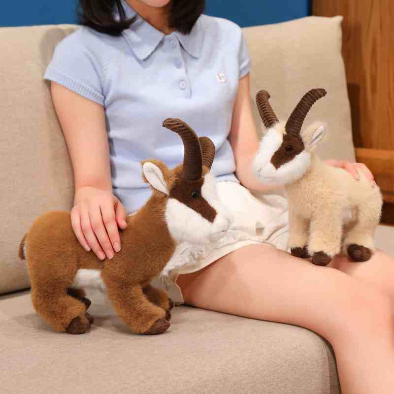 Cozy mountain goat stuffed animal collection displayed with a model on a sofa, suitable for cabin room decor supply.