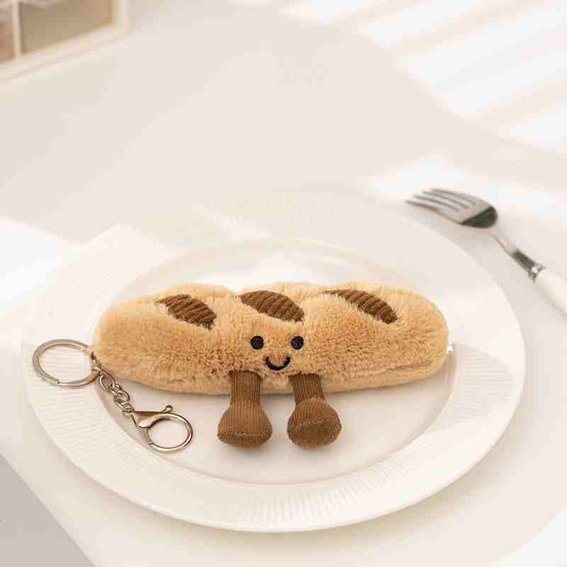 Custom baguette bread plush keychain on a white plate, highlighting quality embroidery for gift shop distributors.