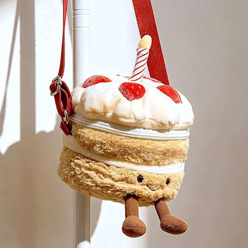 Custom cake plush shoulder bag hanging from a stand showing adjustable strap hardware for OEM manufacturing.