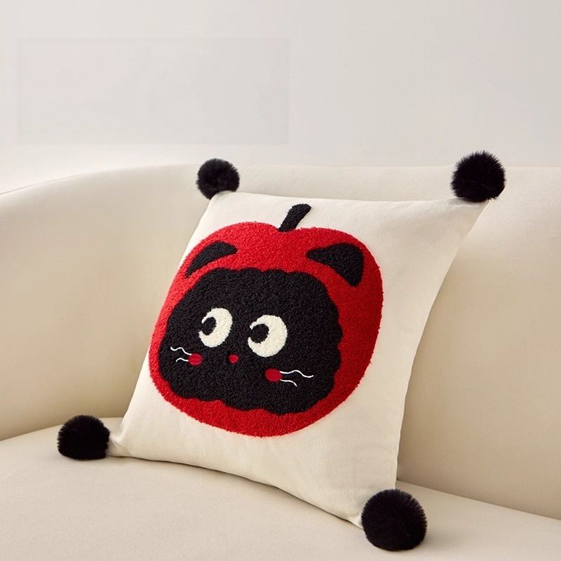 Custom embroidered kitten throw pillow with black pom-poms, angled view for boutique vendors.