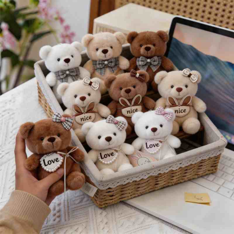 Factory-direct mini teddy bear plush held in hand in front of a basket display, perfect for claw machine prize sourcing and custom private label.