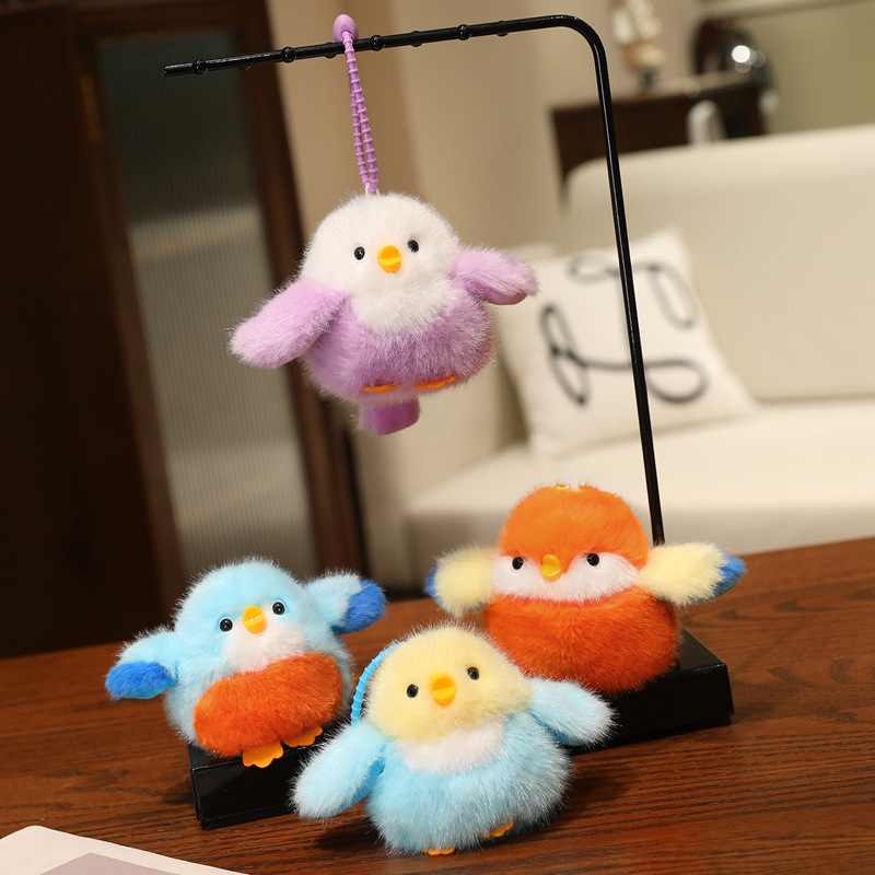 Factory-direct furry bird plush pendants displayed on a stand, perfect for gift shop and bookstore impulse buys.