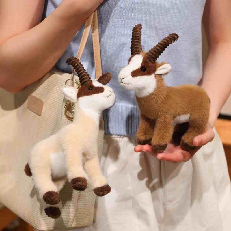 Factory-direct ibex stuffed toy keychain and bag charms held by a model, demonstrating texture for retail vendors.