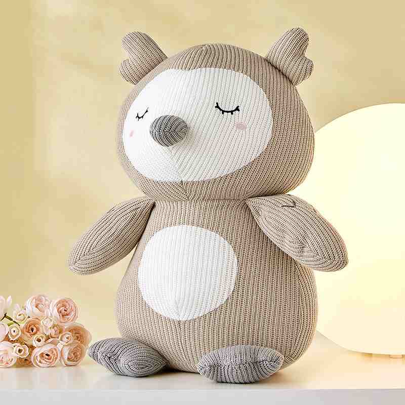 High-ROI beige sleeping owl plushie displayed with pink flowers for worldwide wholesale gift shop sourcing.