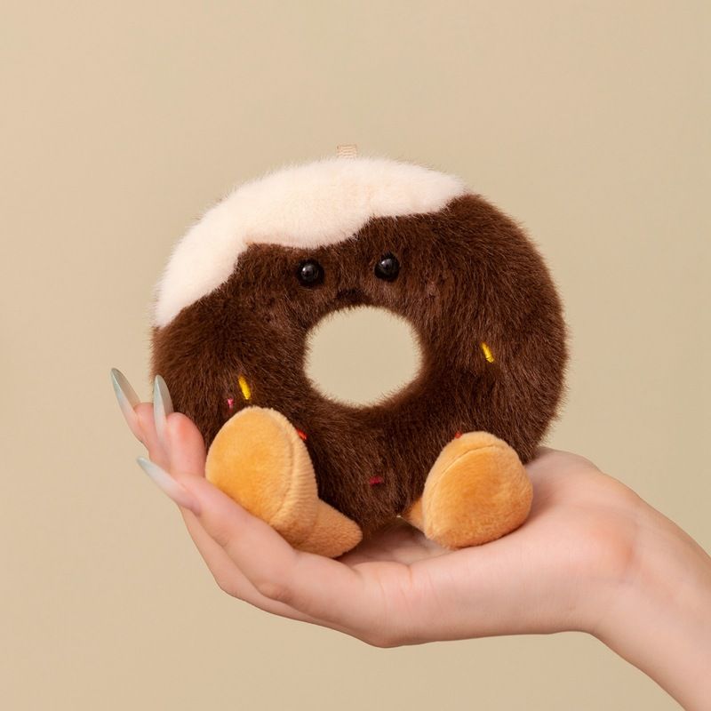 Hand holding a high-ROI kawaii chocolate iced donut plush toy with colorful sprinkles for retail distributors.