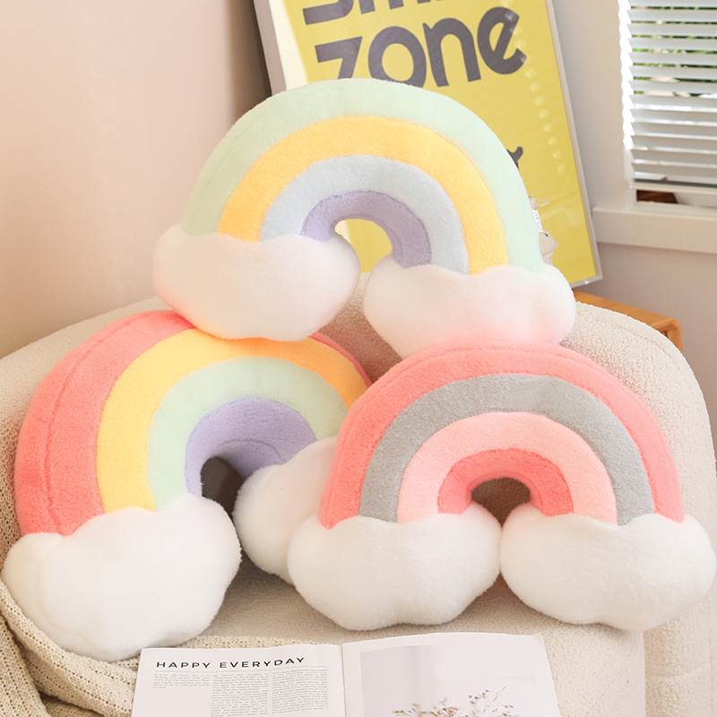 Wholesale kawaii pastel rainbow cloud plush pillows stacked on a sofa, perfect for global nursery decor distributors.