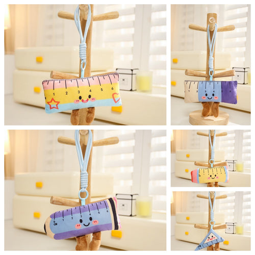 Kawaii school ruler and triangle plush keychain collection with smiling faces, hanging on a wooden stand.