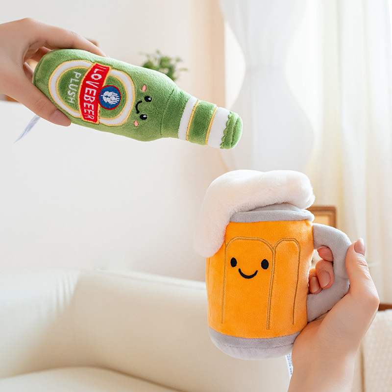Alt Text: Hands holding a funny green beer bottle plush toy and a yellow beer mug stuffed animal to demonstrate actual size and soft texture.