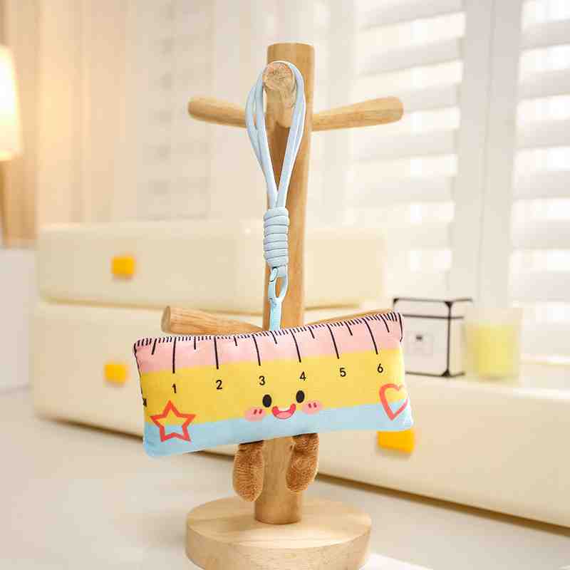 Pastel pink, yellow, and blue rectangular ruler plush keychain with a cute smiling face and star design.