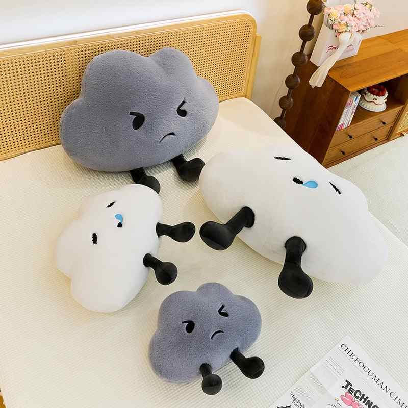 Premium boutique happy and grumpy cloud plushies scattered on bed for wholesale buyers.