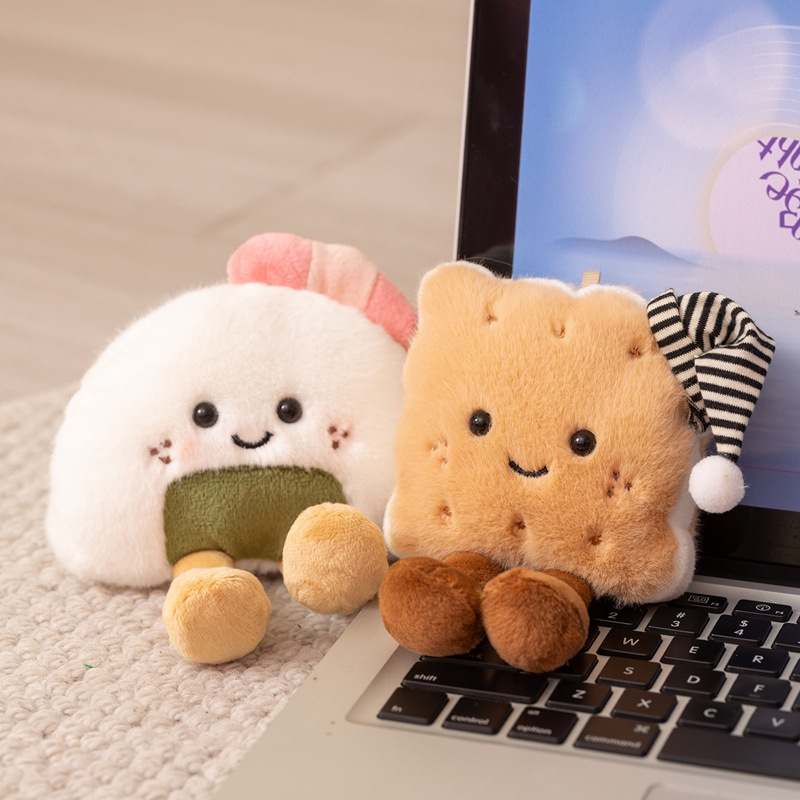 Premium onigiri rice ball and sleep cap biscuit plush toys displayed in front of a keyboard for desk decor suppliers.