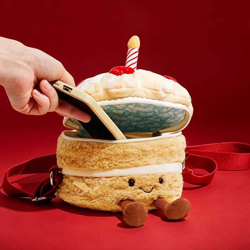 Hand putting a smartphone into the zippered pocket of a private-label plush cake bag showing patterned inner lining.
