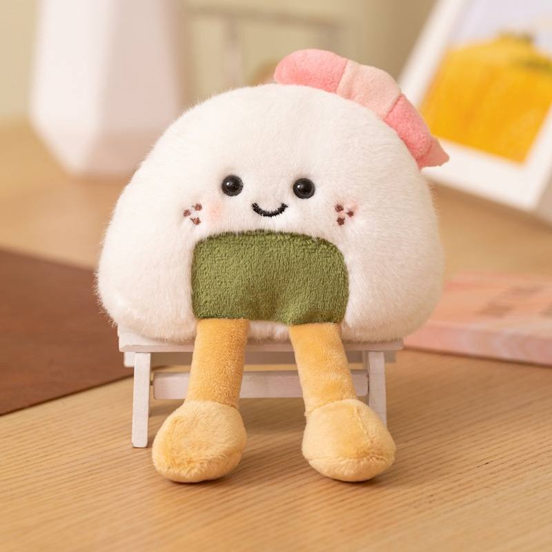 Private-label onigiri sushi rice ball plush cushion with dangling legs resting on a chair for B2B supply.
