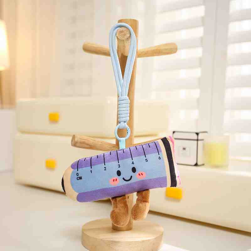 Pastel pink, yellow, and blue rectangular ruler plush keychain with a cute smiling face and star design.