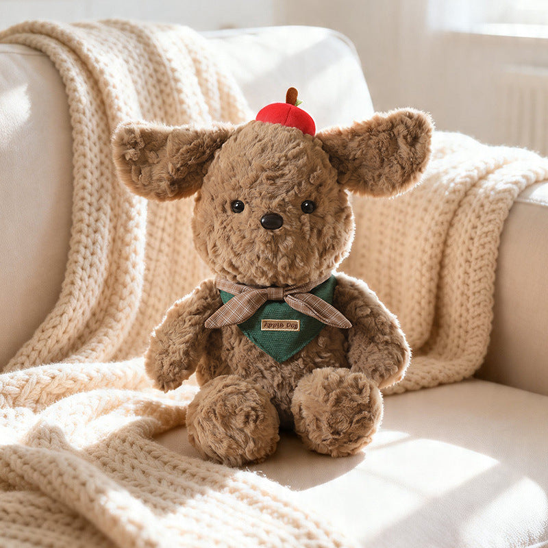 A single, elegant brown plush dog wearing a nature-inspired green plaid bandana and a red apple, resting in a sunlit, minimalist indoor setting. The image highlights sustainable manufacturing, eco-friendly textures, and a sophisticated aesthetic perfect for modern Australian home decor.