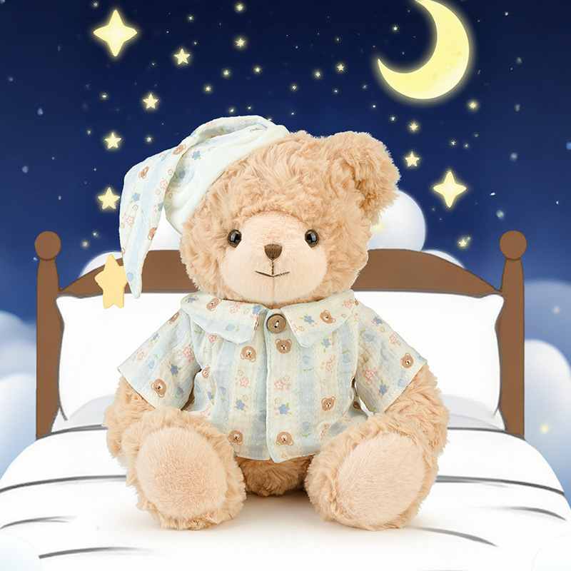 Wholesale bedtime pajama teddy bear plush sitting on a cozy bed with stars and moon background, perfect for nursery decor B2B sourcing.