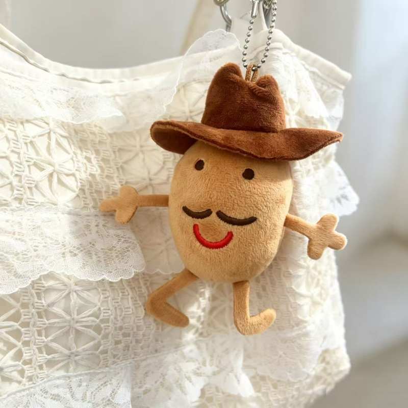 Cute potato plush bag accessory with a red mouth and mustache attached to a summer bag.