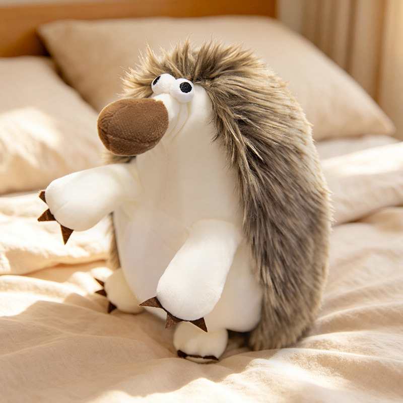 Wholesale funny hedgehog plush toy with big nose sitting on a bed, premium spiky faux fur supply for boutique retailers.