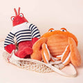 Wholesale nautical lobster in striped shirt and orange crab plush toy assortment resting in a mesh net bag.