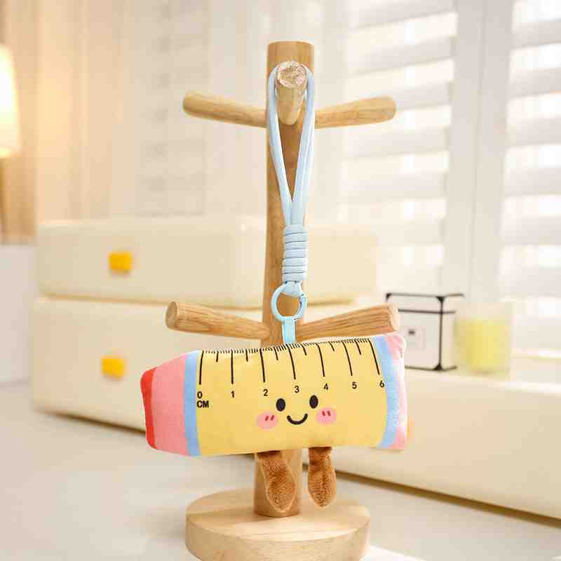 Yellow kawaii ruler plushie bag charm with pink edges, funny soft school supplies aesthetic.